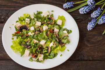 Salad with mushrooms, grilled tomatoes  herbs and feta cheese. Wooden background. Top view