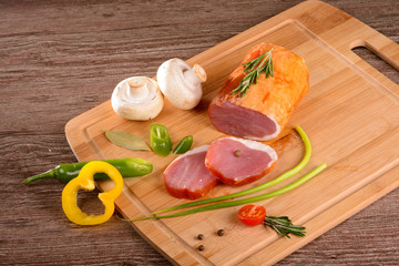 Sirloin smoked sliced piece rests on a wooden Board,lay next to fresh vegetables