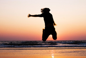Silhouette of a man jumping at the beach during sunset