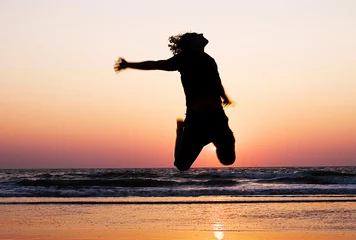 Poster de jardin Mer / coucher de soleil Silhouette of a man jumping at the beach during sunset