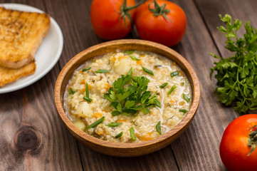 Wheat porridge with meat prepared on a fire in  wooden plate   rustic table. Top view