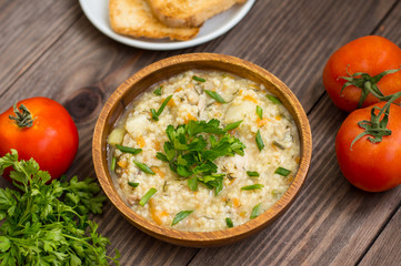 Wheat porridge with meat prepared on a fire in  wooden plate   rustic table. Top view