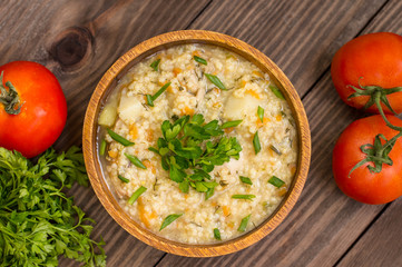 Wheat porridge with meat prepared on a fire in  wooden plate   rustic table. Top view