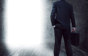 Man with suitcase exiting dark room 