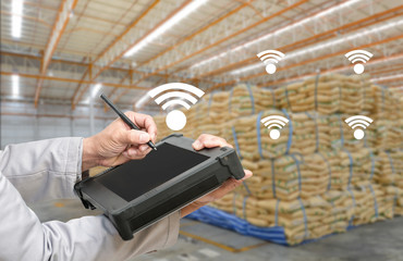 TSmart factory - Rugged computers tablet and Bluetooth barcode scanner in front of modern warehouse in factory use for logistics.