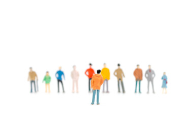 Group of miniature people standing on white background