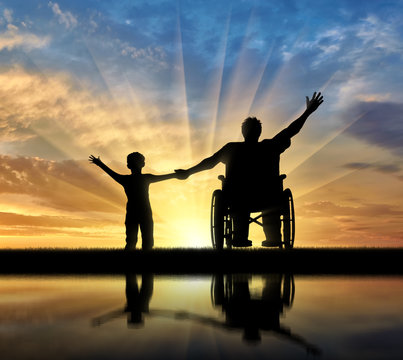 Disabled in wheelchair and his son are happy and their reflection on sunset