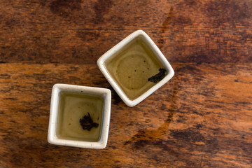 Chinese green tea in square white teacups on a wooden table