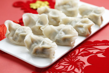 Fototapeta na wymiar Spring Festivl dumplings and paper-cut on red background