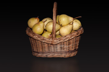 Basket with pears on pure black background.