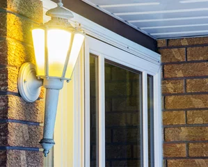 Elegant ornate porch light glowing by front door, welcoming © Rachel Lerch
