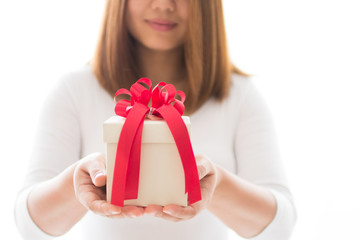 Gift box and red ribbon on hands of woman on white background
