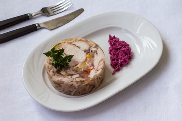 Aspic with meat and horseradish on a white table. Top view. Close-up