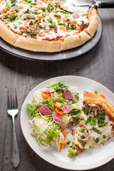 Home made pizza from scratch topped with mushrooms, turkey, kale, peppers, and tomatoes on a plate with salad