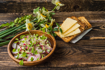 Salad with radishes, apples, greens and a sandwich  fish pate. Wooden background. Top view. Close-up