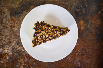 Napoleon cake covered with chocolate and walnuts  raisins on an old table. Top view. Close-up