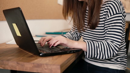 closeup of the hands of young attractive girl uses a laptop in the modern startup office