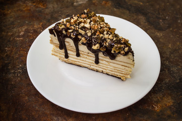 Napoleon cake covered with chocolate and walnuts  raisins on an old table. Top view. Close-up