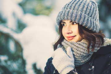 Beautiful young woman in park on snowing winter day.