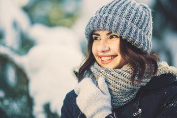 Beautiful happy young smiling woman in park on snowing winter day.