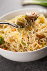 Chinese chicken lo mein with cabbage, carrots, celery, mushrooms, turnips, broccoli, and assorted vegetables with a fork ready to take a bite