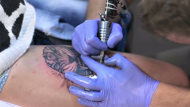 Tattoo artist make tattoo on body at studio. Tattoo parlor. Patterning on skin. Body art