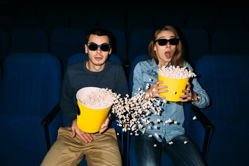 Cinema day. Young couple with popcorn watching interesting movie on their date in cinema. World...