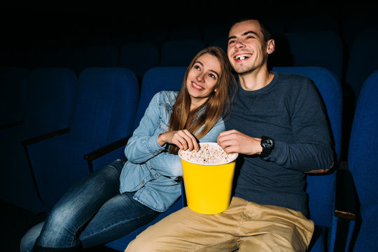 Cinema day. Young happy couple watching funny movie in cinema at their romantic date. World cinema day