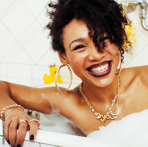 “young afro-american teen girl laying in bath with foam, wearing