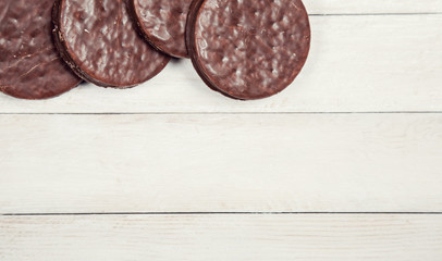 Cookies with chocolate glaze on white wooden background