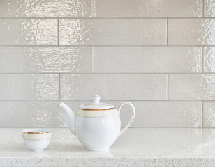 Classic tea pot and a cup on granite counter top against ceramic