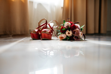 Pair of beautiful women's shoes on the floor. Nearby lies a bouquet of flowers. Probably the wedding day, the bride morning