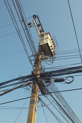 Fototapeta premium Electric pole connect to the high voltage electric wires on blue sky background.