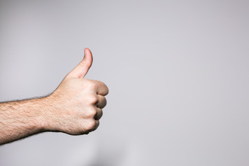 Man's hand doing the thumb up gesture on a white background