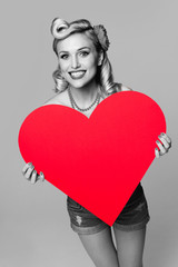 smiling woman holding heart symbol, dressed in pin-up style