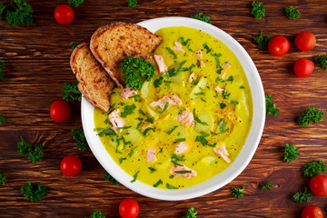 Creamy fish Salmon, leek, potato soup on wooden background