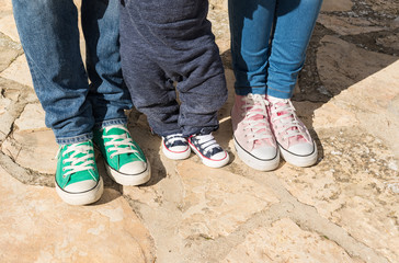 Vista de las piernas y zapatillas de una familia. Madre, padre y bebe 