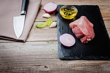  Raw  beef steak and knife on a dark  board. Fresh raw meat with spices.
