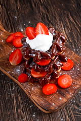 Belgian chocolate waffles with fresh strawberry, whipped cream on wooden table