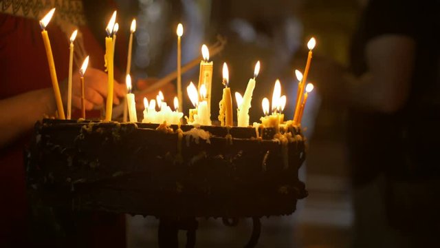 Close up of prayers hands lighting candles in the Holy Sepulchre Church in Jerusalem