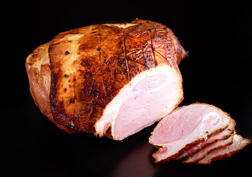 Roasted whole sliced ham on dark background