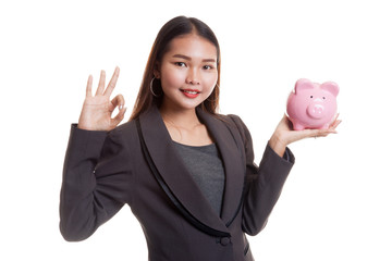 Asian business woman show OK  with pig coin bank.