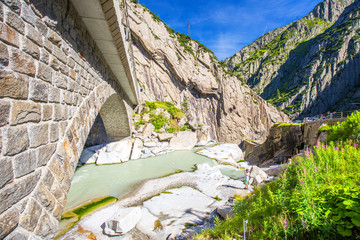Railway bridge Teufelsbrucke over Reuss river in St. Gotthard mountain range of Swiss Alps near...