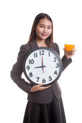 Asian woman with a clock drink orange juice.