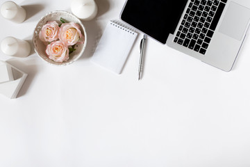 Modern workspace frame with laptop keyboard, vintage tray with roses, notebook, sunglasses in flat lay style. White background. Top view.