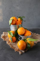 Pile orange fruit with green leaf on grey table of concrete background with copy space. rustic style