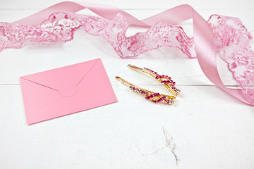 Golden hairpins with pink gemstone and pink lace on white wood