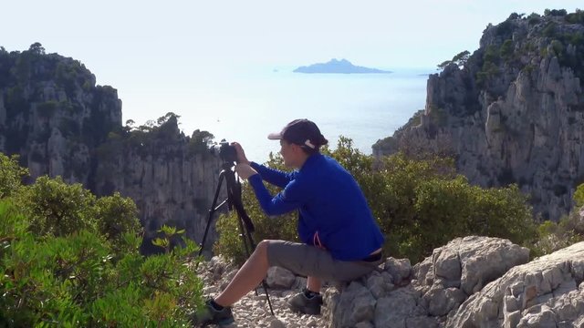 Woman tourist taking photo with digital camera during holiday trip, Calanques, France
