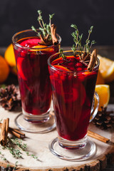 Two glasses of hot mulled wine on a dark background. Spices, oranges and fir cones
