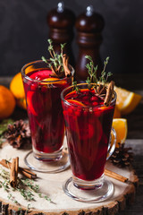 Two glasses of hot mulled wine on a dark background. Spices, oranges and fir cones